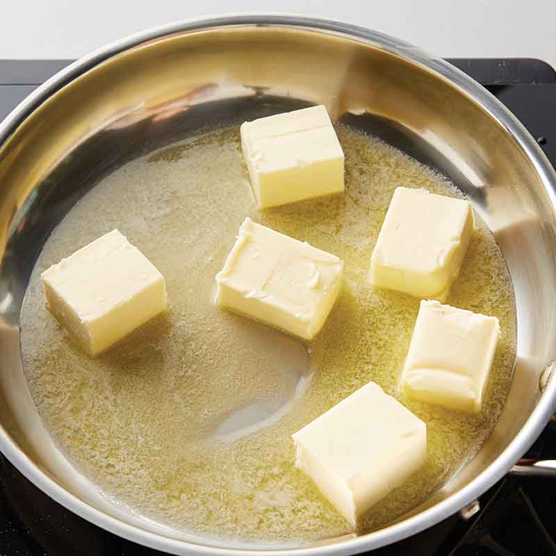 Pieces of butter starting to melt in pan